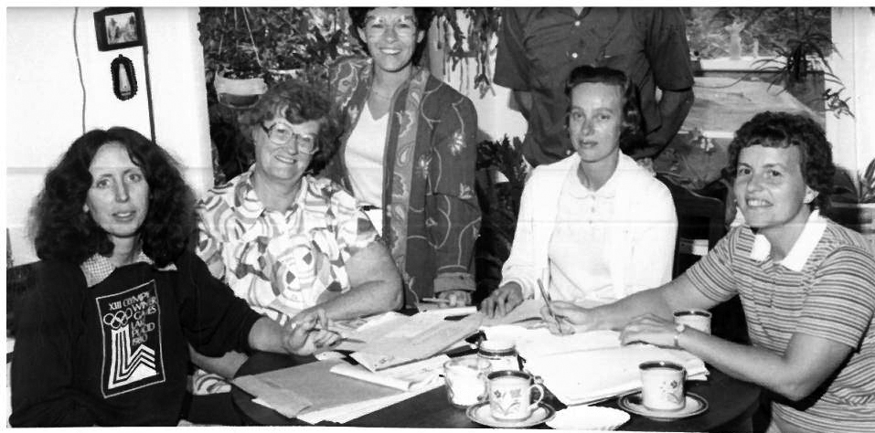 Historic photo of early organizers meeting at a table with paperwork and coffee cups.